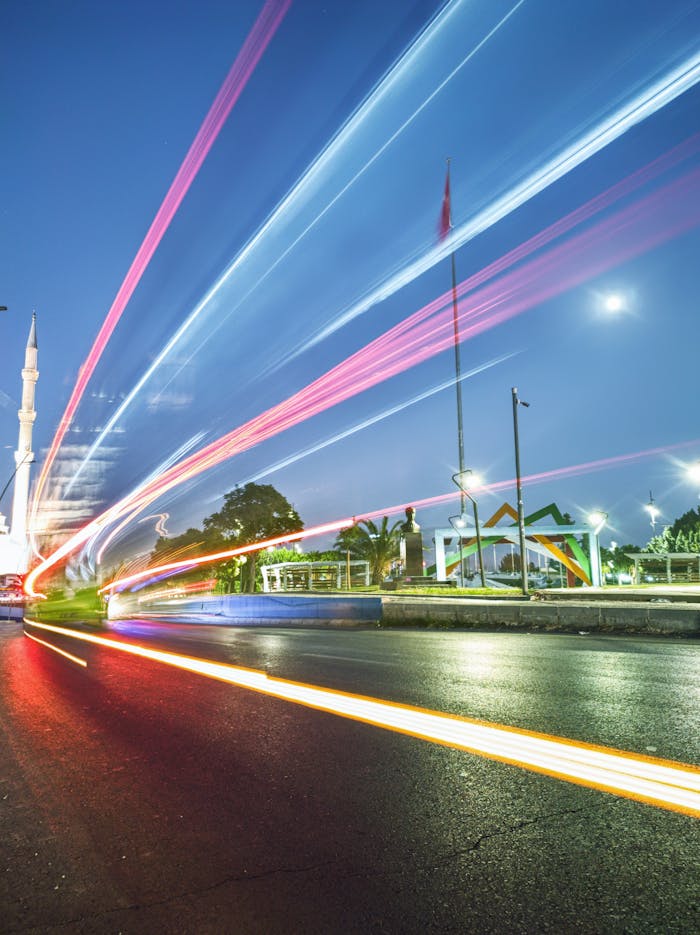 Dynamic city scene with vibrant light trails against a twilight sky and modern architecture.