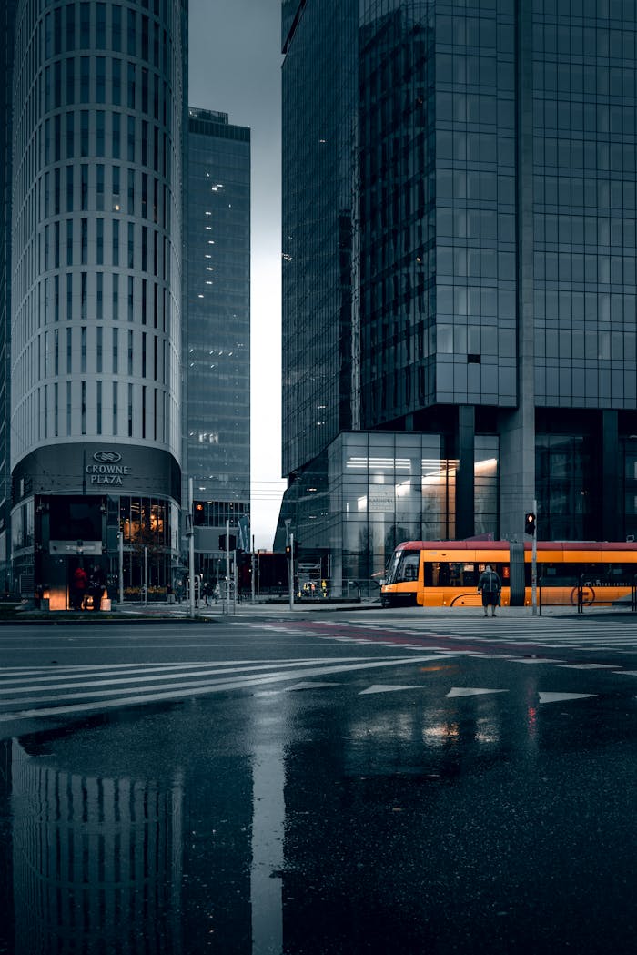 Dark and moody urban scene with reflections, skyscrapers, and a tram in Warsaw, Poland.